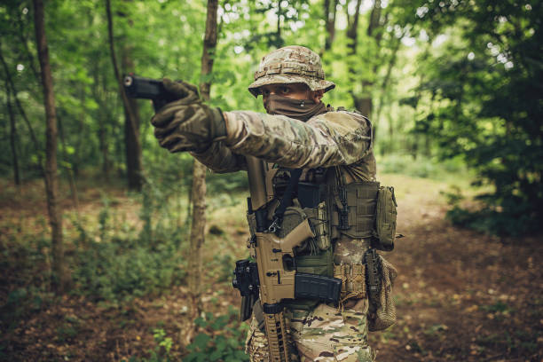 istock Soldier in tactical gear aiming pistol in forest. 2163612824