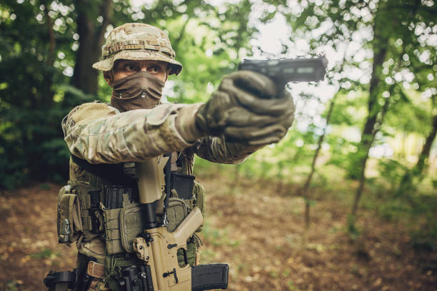 istock Determined soldier aiming pistol in blurred forest. 2163613122