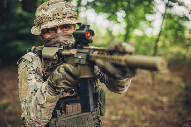 istock Soldier aiming rifle in forest wearing camouflage gear 2163613444