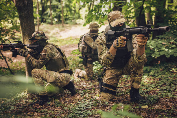 istock Armed soldiers in the dense forest on alert. 2163615768