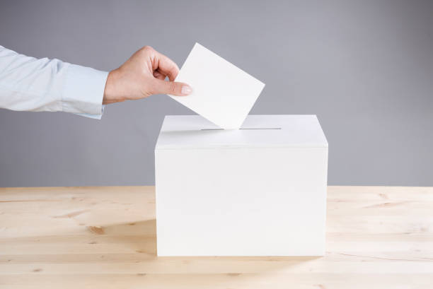 istock Woman's hand casting a vote and a ballot box 2163621401