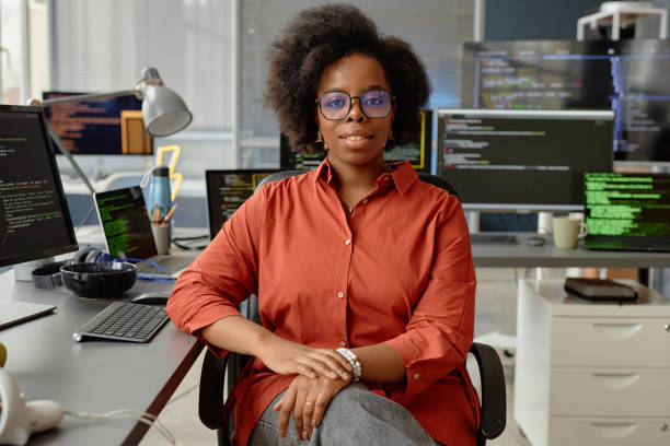istock Female Software Developer in Orange Shirt at Desk 2163621563
