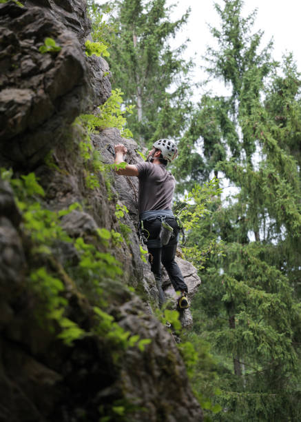 istock Male Climber Ascending Steep Rock Face in Forested Area 2163621668