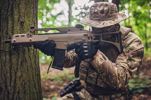 istock Camouflaged soldier aiming rifle behind a tree 2163621674