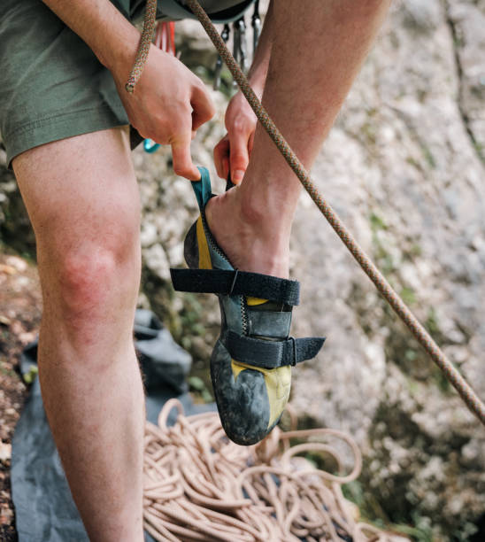 istock Man adjusting climbing shoes on mountain. 2163621691