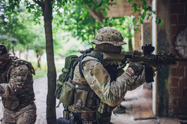 istock Soldier in tactical gear aiming rifle in forest area 2163623144