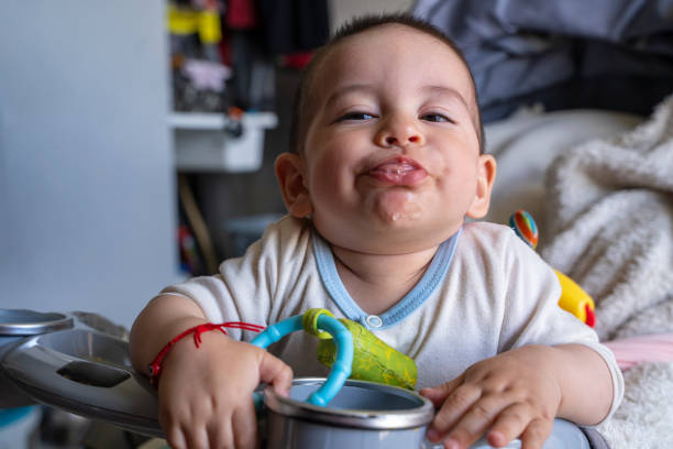 Beautiful baby plays with his father while he tries to take a photo, sticks out his tongue, smiles, and makes cute gestures while sitting in his baby stroller