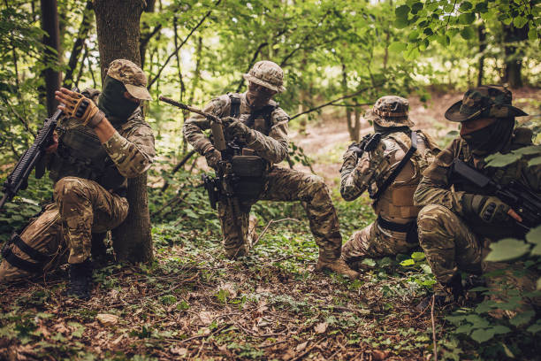 istock Four camouflaged soldiers on high alert in forest. 2163626506