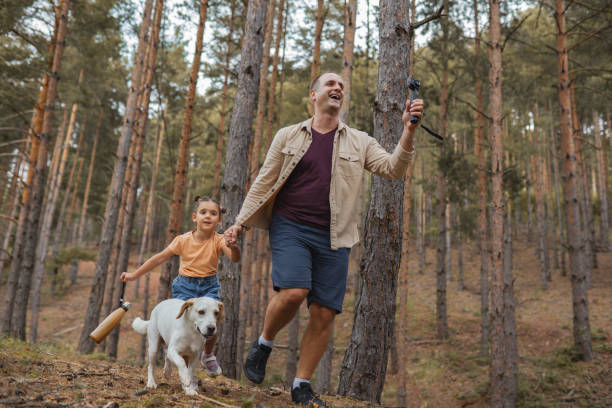 istock Father and daughter running with dog in forest 2163626736
