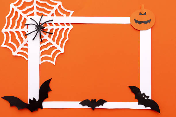 istock Halloween white frame with white spider web, paper black bats and pumpkin on an orange background. Flat layout with copy space 2163627607