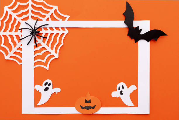 istock Halloween greeting white frame with white spider web, paper ghosts, black bat and pumpkin on an orange background. Flat layout with copy space 2163627612