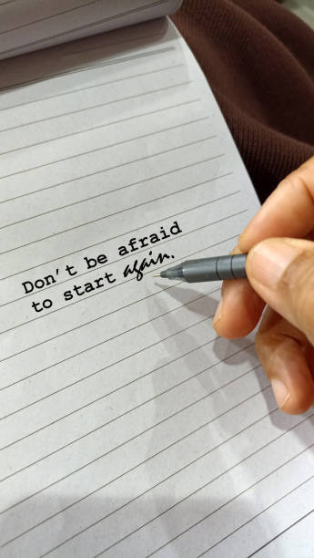 istock Person pointing motivational words on a paper - Don't be afraid to start again. 2163632634