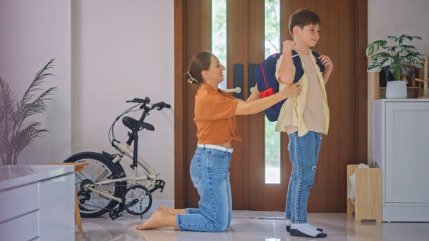 A mother talks lovingly with her son before school in the morning at the front door