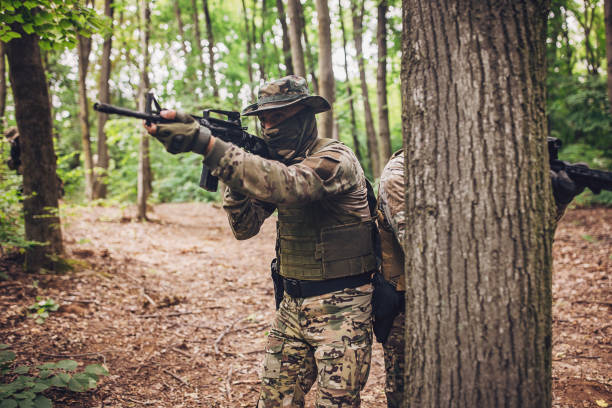 istock Soldier aiming rifle, another hiding behind tree. 2163632822