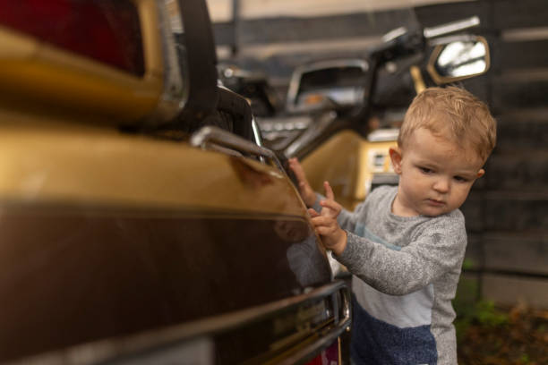 A cute little boy is standing next to a motor scooter and admiring it