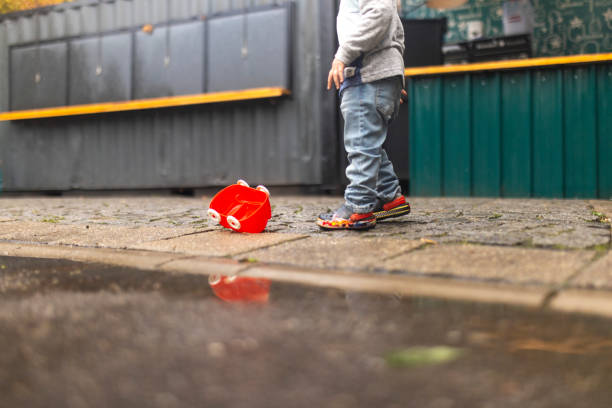 An unrecognizable toddler boy is playing outdoors during an autumn day