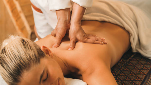 Attractive caucasian woman having back massage at warm sauna room. Tranquility. Beautiful caucasian woman having back massage in front of wooden sauna cabinet. Attractive woman feel deep in relaxation surrounded by aroma and essential oil. Relaxing and calm concept. Tranquility. swedish sauna stock pictures, royalty-free photos & images
