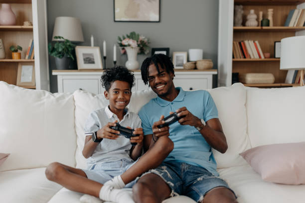 istock Father and son gaming on couch with bright smiles 2163635534