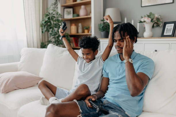 istock Son celebrates gaming victory while father playfully reacts 2163635668