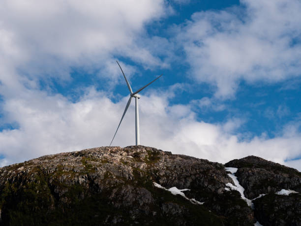 One single windturbine on top of a mountain with cloudy sky as a background