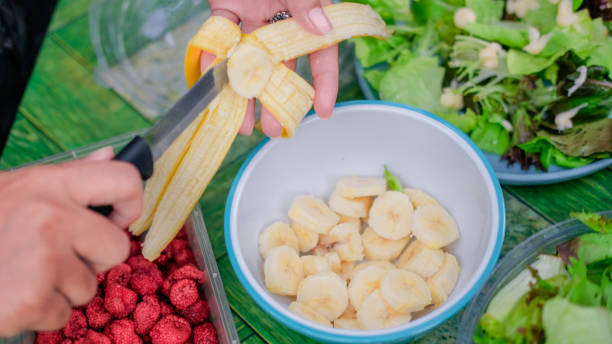 After a day of exploring the urban forest, a young woman prepares a vibrant and healthy meal, featuring a fresh salad and an assortment of fruits. The image captures her in a moment of nourishment and rejuvenation, reflecting the harmony between outdoor adventure and mindful eating. Surrounded by the natural beauty of her surroundings, this scene highlights the rewarding experience of combining physical activity with healthy living.