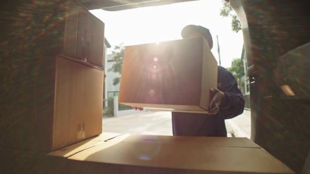 Delivery courier loading cardboard boxes packages into her car. Asian woman delivery courier loading cardboard boxes packages into her car trunk. Moving Service stock pictures, royalty-free photos & images