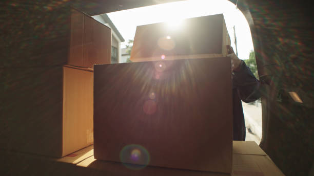 istock delivery person taking cardboard box from van for delivery. 2163647398