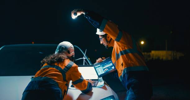 istock Team of engineers illuminated only by the light of flashlight and laptop screen work intently on renewable energy project after dark. Green ecological power generation wind sustainable energy. 2163655254