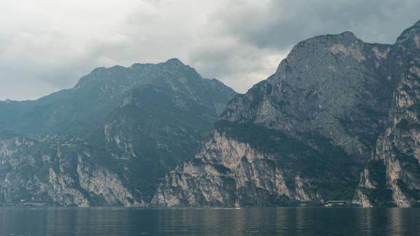 The serene blue of Lago di Garda contrasts beautifully with the rugged mountain range in the background, offering a perfect blend of natural beauty.