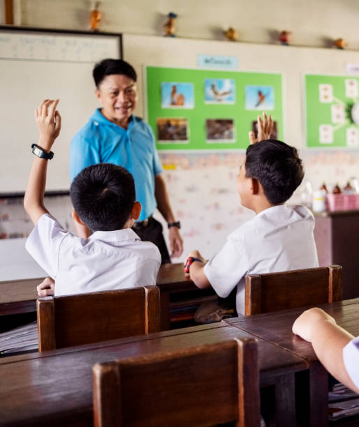 istock School classroom with pupils raising hands to answer the question 2163657118
