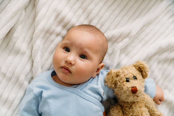 istock Sweet baby lying on blanket with her teddy bear and looking at camera 2163659813