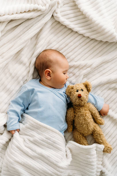 istock Sweet baby lying on blanket with her teddy bear and sleeping 2163659861