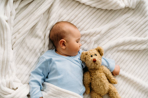 istock Sweet baby lying on blanket with her teddy bear and sleeping 2163659874