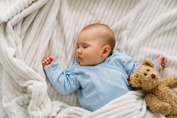 istock Sweet baby lying on blanket with her teddy bear and sleeping 2163659902