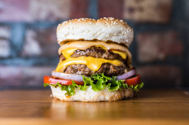 istock Grilled Double Beef Burger include grill beef patty, mayonnaise, lettuce leaf, tomato and onion isolated on wooden board side view of unhealthy junk fastfood 2163664844