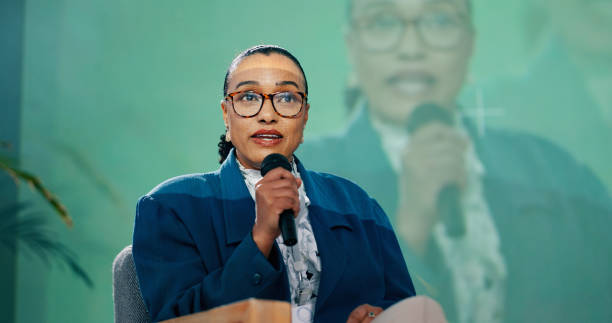 istock Conference, forum or speech and public speaking woman with microphone on stage for development seminar. Business, presentation and workshop with motivational speaker person in corporate auditorium 2163665336