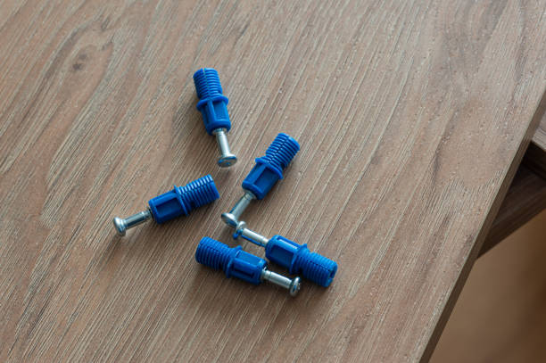 Blue plastic anchors and metal screws on a wooden surface