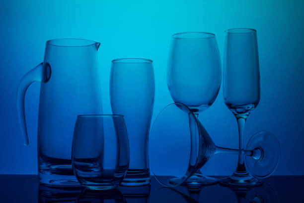 Glassware collection on a blue background, including a pitcher, tumblers, and stemmed glasses