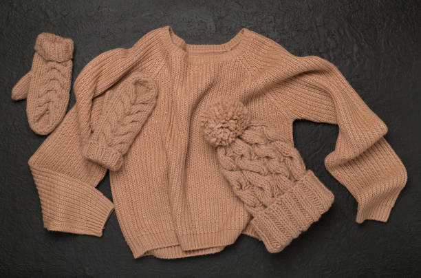 istock Sweater and winter hat with mittens on concrete background, top view. 2163669340