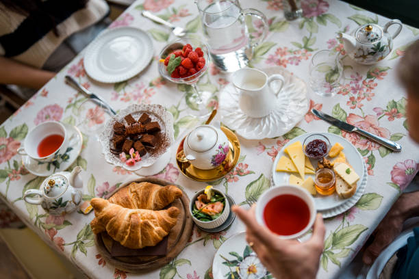 A diverse array of morning delights features croissants, fresh berries, and a pot of tea, set on a floral-tabled boutique hotel, reflecting a leisurely breakfast ambiance.