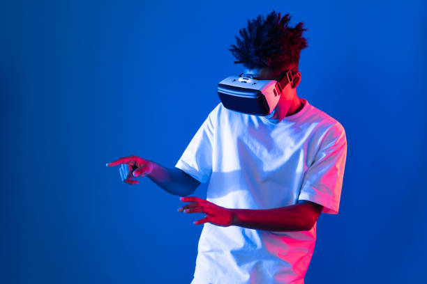 istock Young African player wearing VR point hologram 3D neon light wall. Contrivance. 2163669862