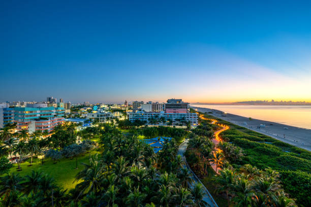 Famous South Beach Illuminated During a Vibrant Sunrise with a Colorful Lifeguard Hut Sitting On the Beach in Miami, Florida USA Famous South Beach during a vibrant sunrise with a colorful lifeguard stand sitting on the beach in Miami, Florida USA pretty beach house stock pictures, royalty-free photos & images