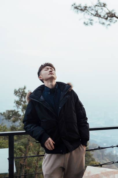 istock A man leaning against a railing in winter, feeling nature 2163670204