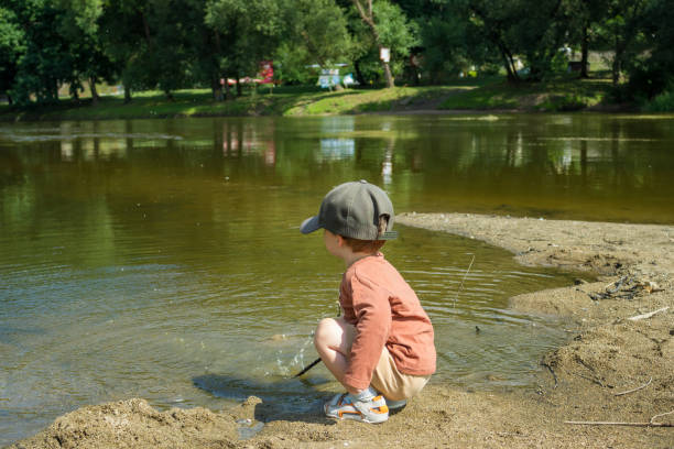 Cute elementary age boy walking in city park on sunny summer day