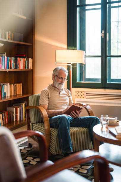 istock Smiling Elderly Man Reading with Coffee in Hotel Lounge 2163671810