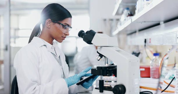 istock Tablet, research and woman with microscope, science and check experiment for cancer treatment. Person, scientist and employee with lab equipment, online results and cure development with digital app 2163672001