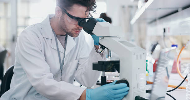 istock Test, research and man with microscope, science and check experiment for cancer treatment. Person, scientist and employee with lab equipment, biotech and cure development with sample and studying 2163672003