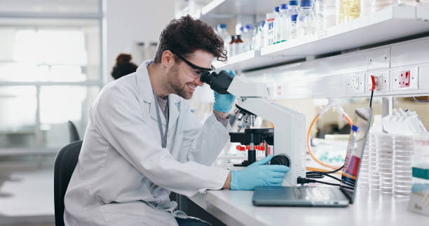istock Biotech, research and man with microscope, science and check experiment for cancer treatment. Person, scientist and employee with lab equipment, vaccine or sample for monkeypox and studying particles 2163672007