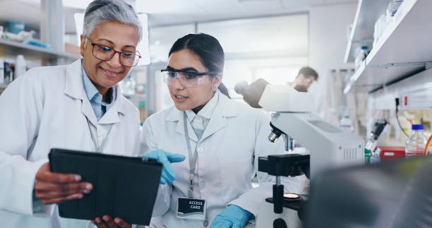 istock Science, team and tablet in lab for research, vaccine development or online feedback. Women, technology or discussion at microscope for test results, medical report or virus study for pharmaceuticals 2163672052