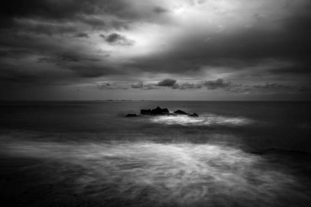 waves hitting rocks in the sea on a cloudy day